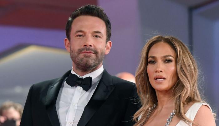 A formal event portrait of Ben Affleck and Jennifer Lopez standing side by side in elegant evening attire.