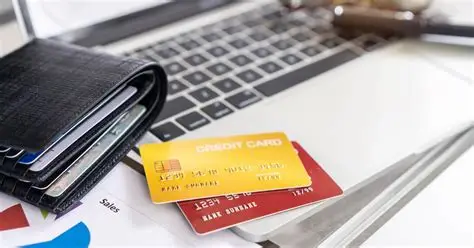 Wallet and colorful credit cards placed on a laptop keyboard with financial charts underneath, symbolizing online money management and rising credit card expenses