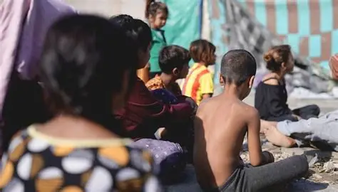 Children sitting on the ground in a makeshift shelter in southern Lebanon, reflecting the growing humanitarian crisis and rising risk of hunger.