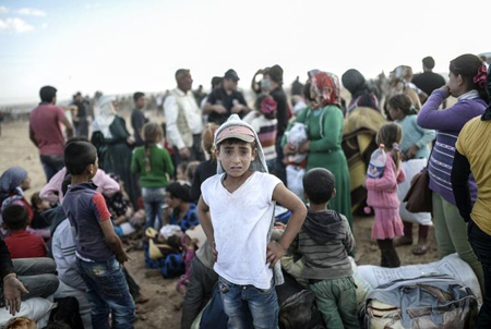 Displaced families gathered in a dusty open area in southern Lebanon, with children standing among bags and belongings during the ongoing humanitarian crisis.