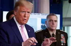 Government and military officials speaking during a formal press briefing, with one civilian leader addressing the audience beside a decorated military officer.
