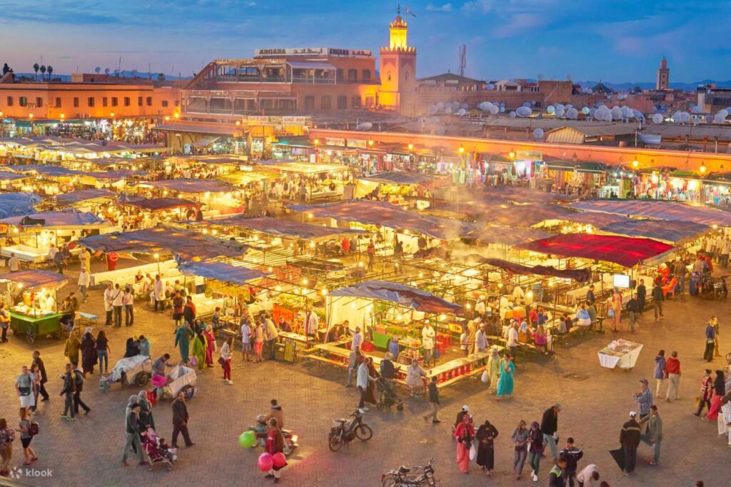 Marrakech and the High Atlas – evening view of The Souks with vibrant market stalls, lights, crowds, and traditional Moroccan architecture.