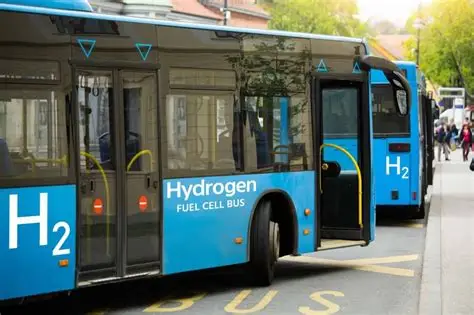 Two hydrogen fuel‑cell buses parked at a city stop, featuring H₂ markings and zero‑emission electric propulsion.