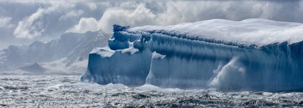 Antarctica Ice Sheet Collapse illustrated by a giant tabular iceberg Antarctica Ice Sheet Collapse – massive tabular iceberg drifting in polar waters