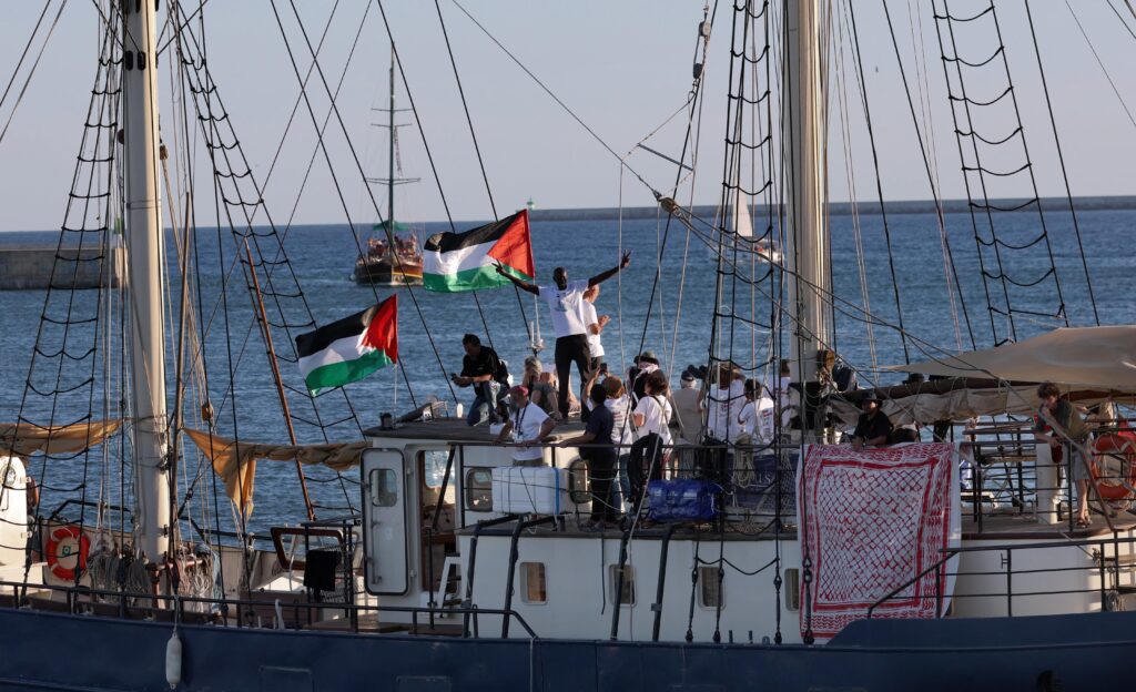Palestinian‑flagged vessel with activists participating in a maritime demonstration Sailing vessel displaying multiple Palestinian flags with activists gathered on deck during a maritime demonstration