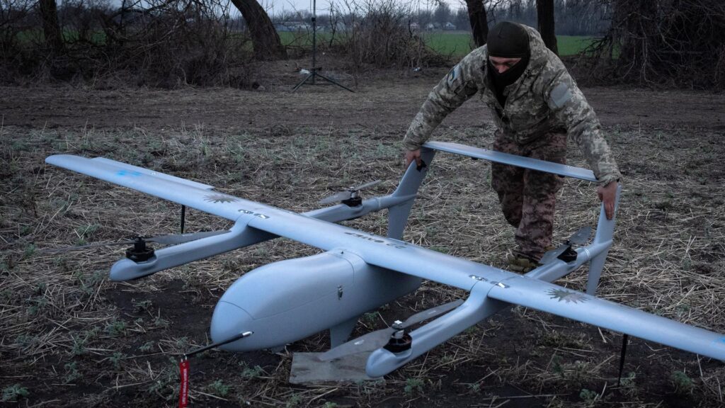 Ukraine Drone Attacks – Military Operator Prepares Reconnaissance Drone for Field Mission Ukraine drone attacks military operator preparing reconnaissance drone in a rural field