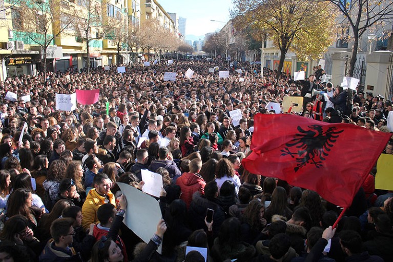 A large crowd of Albanian protesters filling a central boulevard in Tirana, waving the national flag during nationwide demonstrations.